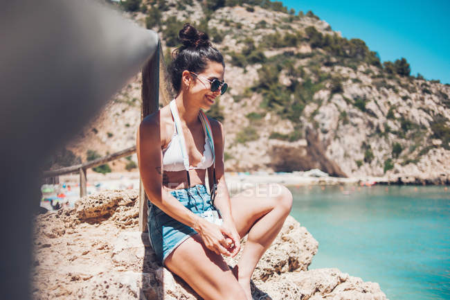 Young girl in summer clothes leaning on wooden handrail on beach — Stock Photo