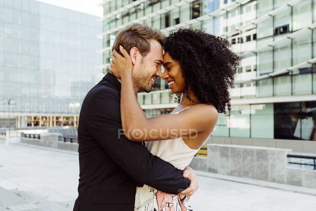 Elegante casal multirracial abraçando na cidade moderna — Fotografia de Stock