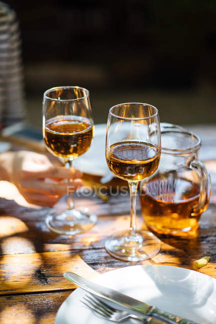 Human hand holding glass of white wine on wooden table outdoors — Stock Photo