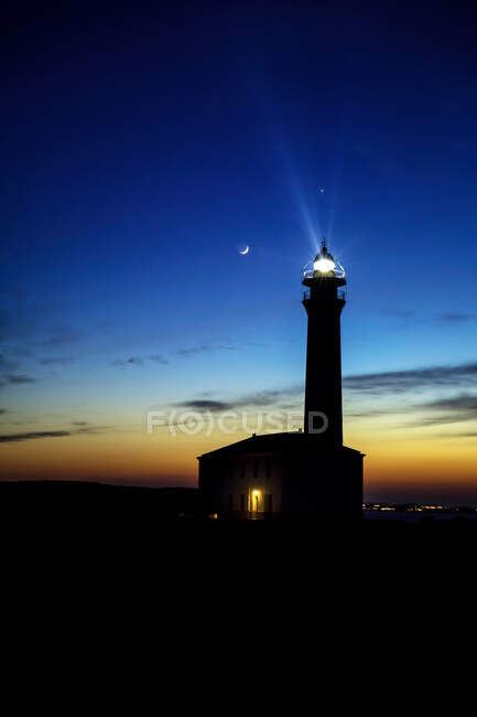 Sea lighthouse with the moon in the backgroun, Menorca, Spain — Stock Photo