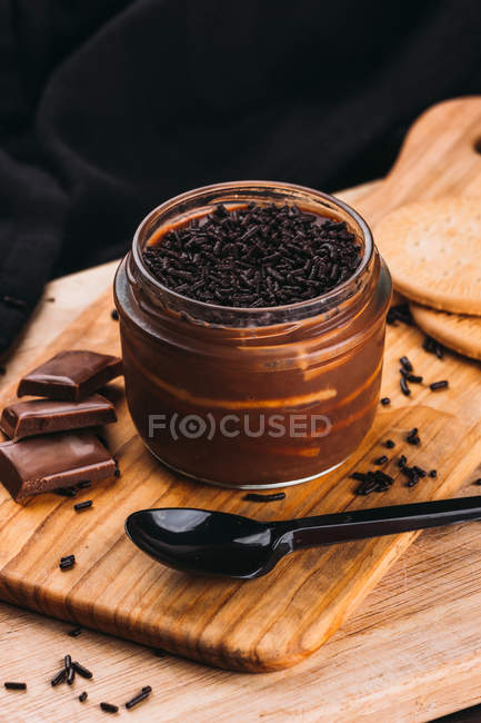 Sobremesa de musse com chocolate em jarra em tábua de madeira — Fotografia de Stock