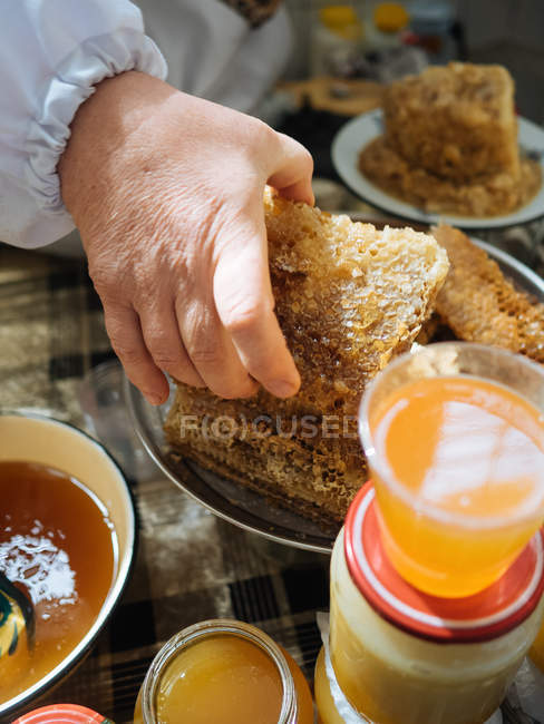 Крупным планом человеческой руки, берущей кусочек соты с тарелки — стоковое фото