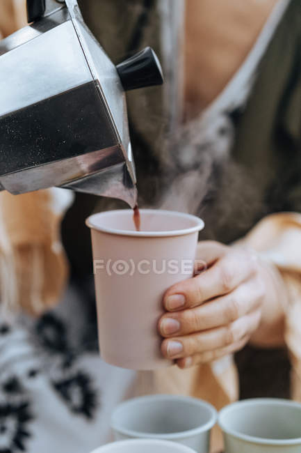 Female hands pouring freshly brewed coffee from coffee maker into cups at picnic — Stock Photo