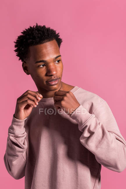 Hipster black man posing on pink background and looking away — Stock Photo