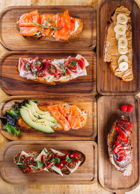 Ассортимент питательных и сладких сэндвичей на деревянной доске — стоковое фото