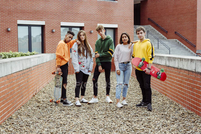 Gruppo multietnico di adolescenti in abiti casual con skateboard in piedi sulla strada e guardando la fotocamera — Foto stock
