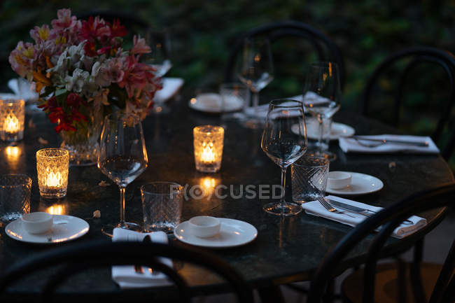 Setting table decorated with candles and flowers at night — Stock Photo