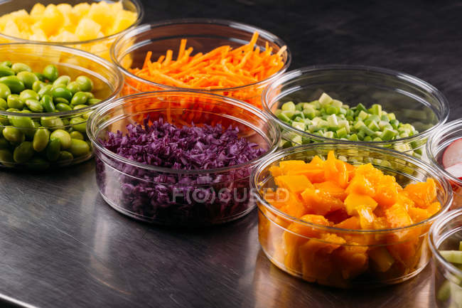 Set of plastic bowls of assorted vegetarian ingredients for food preparation — Stock Photo