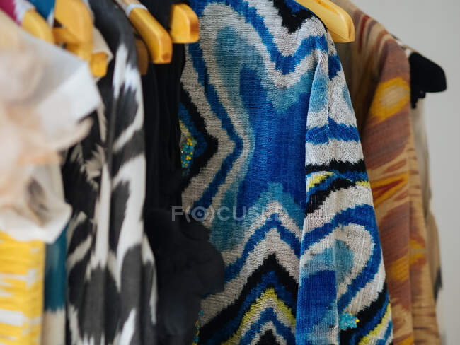 Colorful different indigenous dresses hang on wooden hangers — Stock Photo