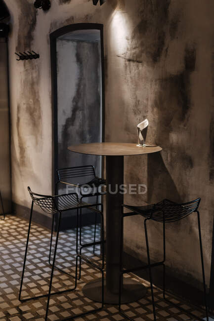 Интерьер современного кафетерия с простой мебелью из табуретов и столом рядом с потрепанной декоративной стеной — стоковое фото