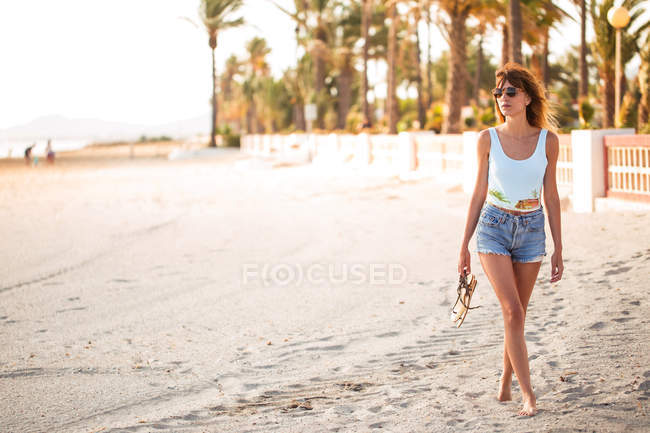Schlanke Frau in Sommerkleidung schlendert am tropischen Strand — Stockfoto