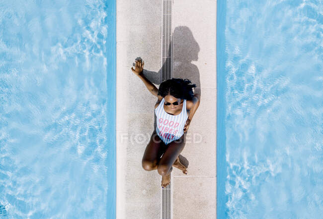 Bonita mujer africana en traje de baño en la piscina. - foto de stock