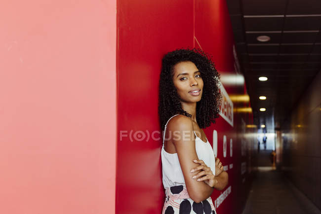 Afrikanisch-amerikanische Frau im eleganten Outfit steht auf rotem Hintergrund — Stockfoto
