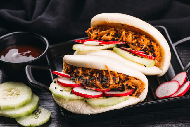 Bao of fried pork and vegetables on tray on black background — Stock Photo