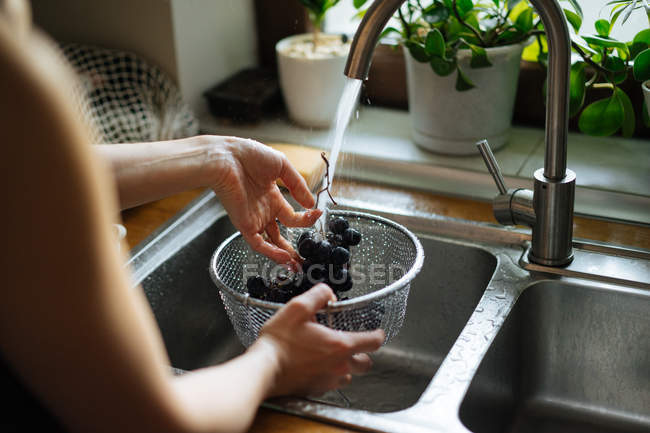 Mãos humanas lavar uvas sob pia torneira na cozinha — Fotografia de Stock