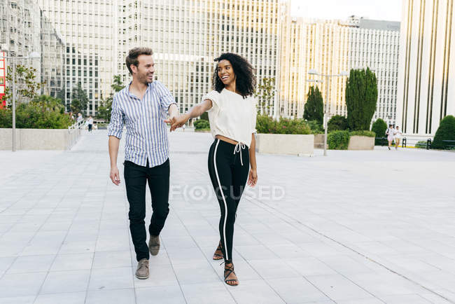 Feliz pareja caminando en la calle tomados de la mano - foto de stock
