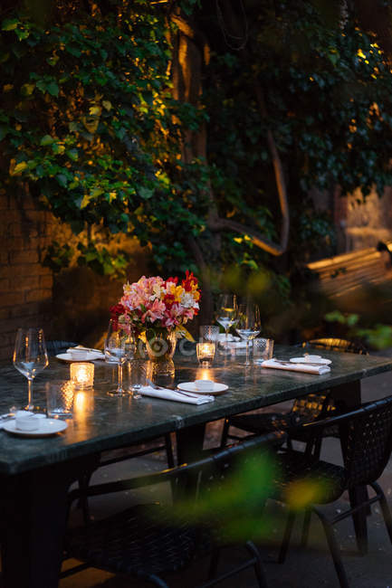 Apparecchiare la tavola decorata con candele e fiori di notte sul cortile — Foto stock