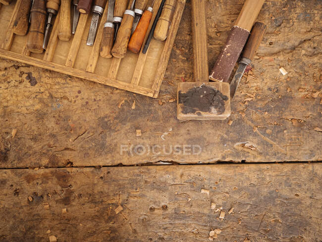 Сверху снимок потрепанного деревянного стола с набором ремесленных инструментов для резьбы по дереву, Узбекистан — стоковое фото
