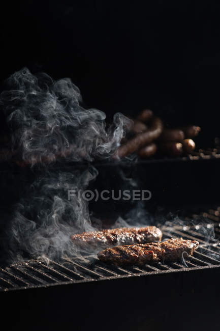 Galettes de hamburger cru rôtissant sur grille de barbecue à l'extérieur — Photo de stock