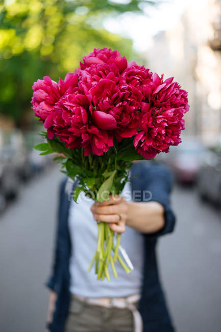 Donna in possesso di bouquet di peonie rosa davanti al viso — Foto stock