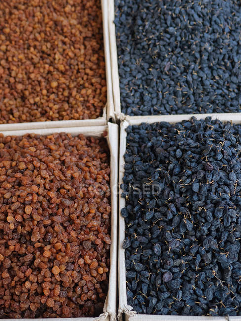 Cajas de uvas pasas marrones y negras en el mercado agrícola - foto de stock