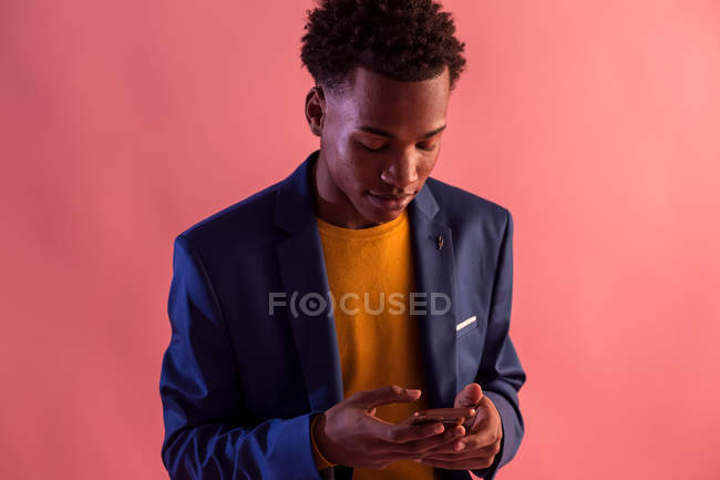 Trendiger Party-Mann surft Smartphone auf rotem Hintergrund — Stockfoto
