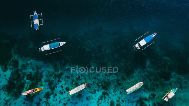 Вид с воздуха на небольшие красочные лодки, плывущие по спокойной лазурной поверхности океана — стоковое фото