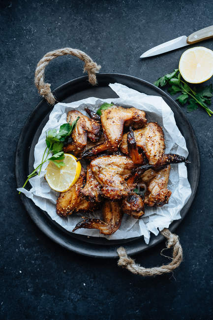 Baking dish of baked chicken wings in sesame and parsley with lemon — Stock Photo