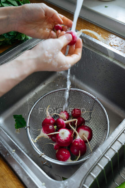 Mujer lavando verduras frescas en la cocina - foto de stock