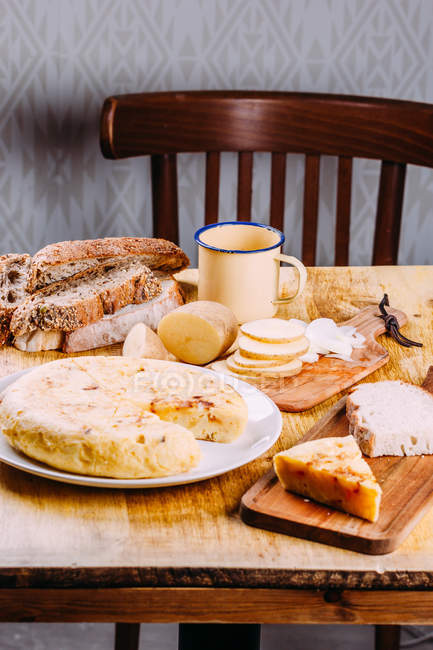 Torta fresca tagliata su piatto su tavola di legno con taglieri, pane e verdure a fette — Foto stock