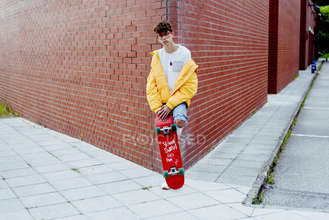 Підліток зі скейтбордом на розі — стокове фото