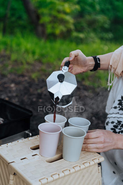 Les mains féminines versant le café fraîchement infusé de la cafetière dans des tasses au pique-nique — Photo de stock