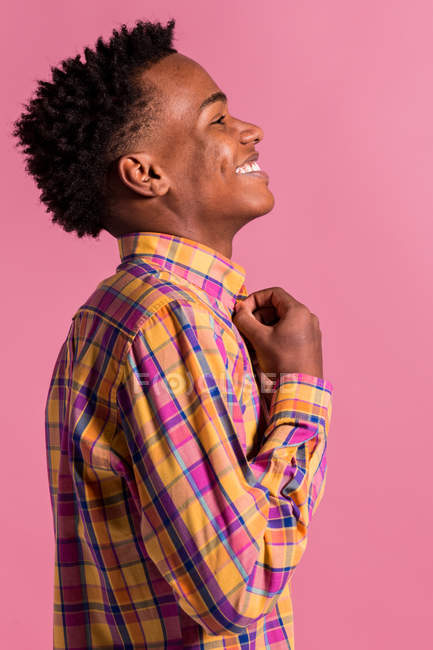 Laughing hipster black man in colorful shirt on pink background — Stock Photo