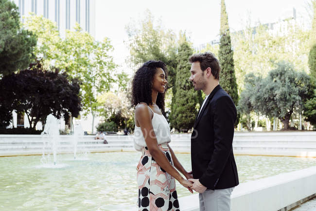 Cute elegant couple holding hands near fountain — Stock Photo