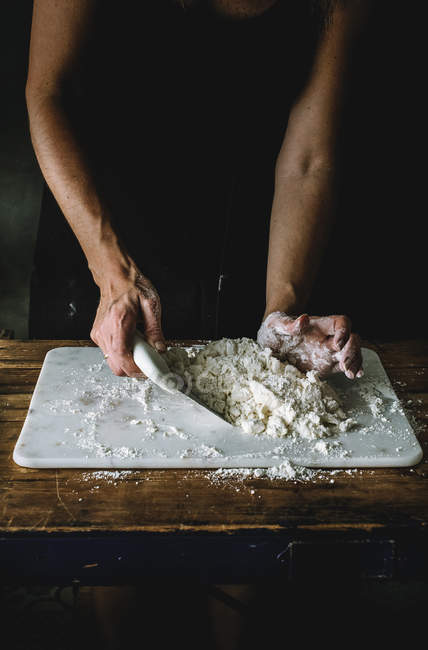 Обрезанный снимок женщины, смешивающей кучу муки с маслом на мраморной доске во время приготовления пищи — стоковое фото