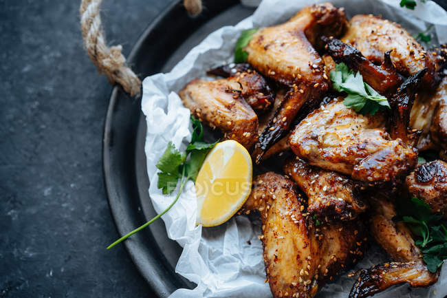 Close-up of baking dish of baked chicken wings in sesame and parsley with lemon — Stock Photo