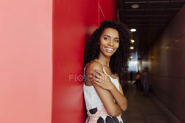 Sonriente mujer afroamericana en traje elegante de pie sobre fondo rojo - foto de stock