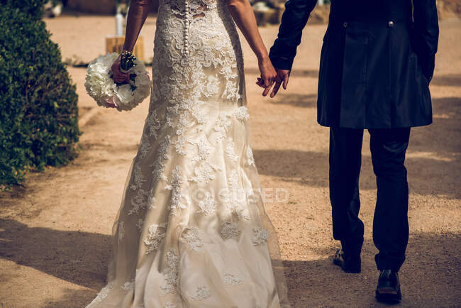 Coppia sposata in abiti da sposa che si tiene per mano — Foto stock