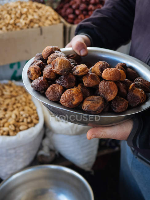Person holding metal bowl of dried figs at farmer market — Stock Photo
