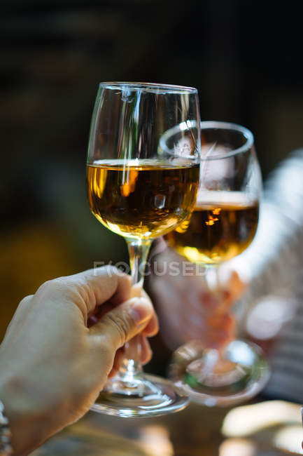 Human hands clinking delicate glasses with white wine outdoors — Stock Photo