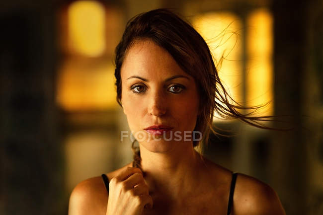 Mujer joven tierna en luz suave mirando a la cámara - foto de stock