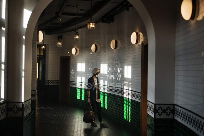 Stilvolle Frau spaziert durch geflieste Halle — Stockfoto