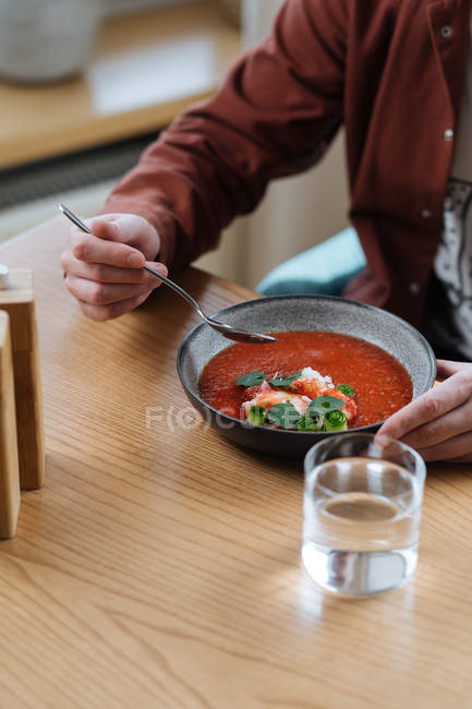 Man eating traditional Nordic red soup garnished with herbs — Stock Photo