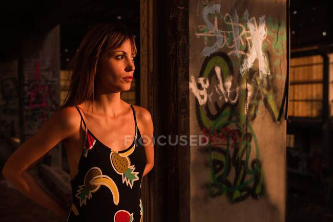 Riflessivo giovane donna in costume da bagno in piedi in grunge interno — Foto stock