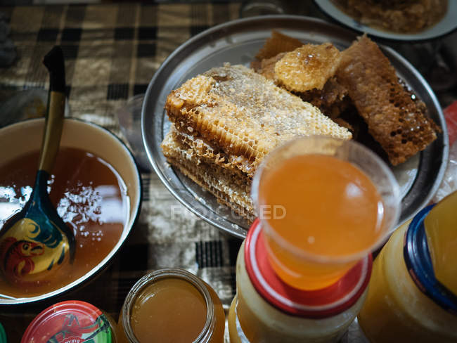 Close-up of honeycomb on plate and jars of fresh honey on rustic table — Stock Photo