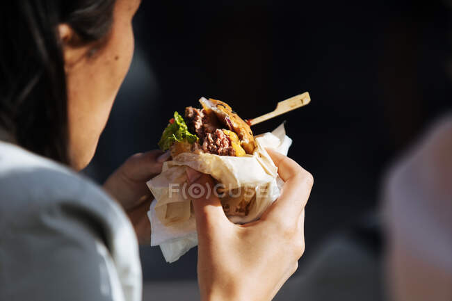 Close-up de pão preto em hambúrguer com suco de carne e picles — Fotografia de Stock