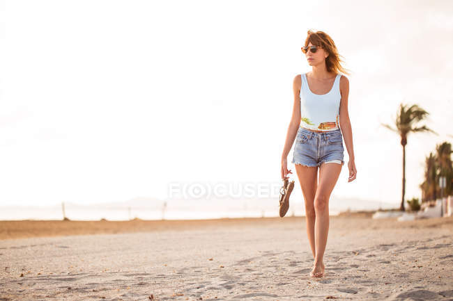 Slim donna in abiti estivi passeggiando sulla spiaggia tropicale — Foto stock