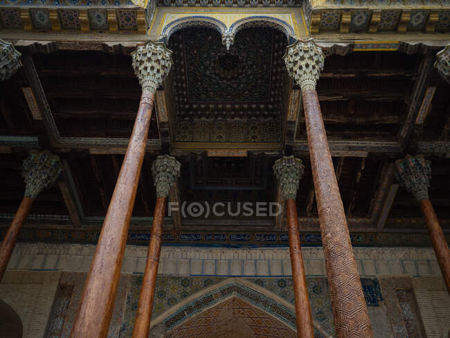From below shot of colorful carved ceiling with thin columns of mosque, Uzbekistan — Stock Photo