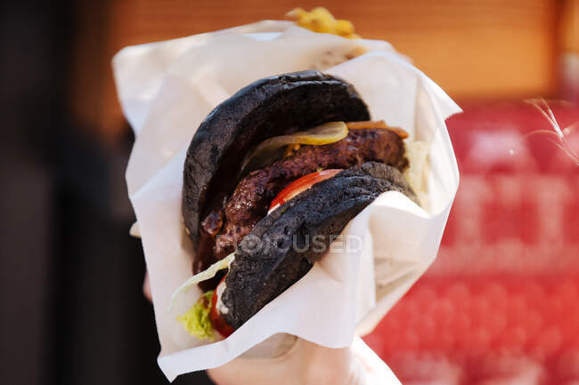 Gros plan de pain noir dans un hamburger avec galette de viande de jus et cornichons — Photo de stock
