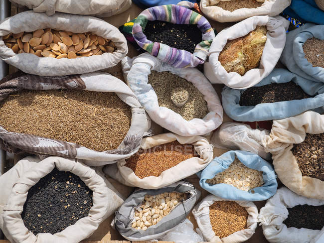 Bolsas llenas de diversos granos y especias aromáticas y condimentos en el mercado de los agricultores - foto de stock